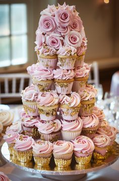 a tower of cupcakes with pink frosting roses on top and gold trim around the edges