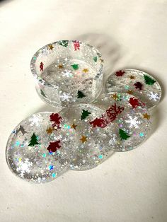 four clear glass dishes with christmas decorations on the rims and one is filled with confetti