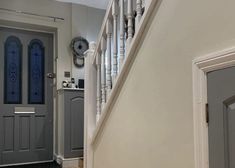 an entry way with two doors and a clock on the wall next to it's banister