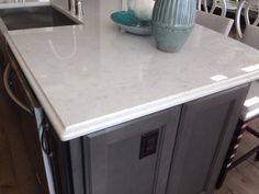 a kitchen counter top with a vase on it and chairs in the backround