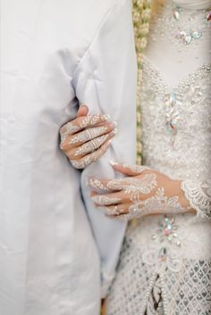 two people dressed in white holding each other's hands