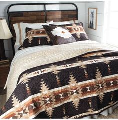 a bed with a brown and white quilt on it's headboard next to a night stand