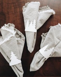 four napkins with trees cut out of them on top of a wooden table,