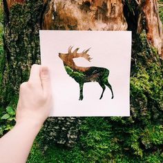 a hand holding up a piece of paper with an image of a deer on it