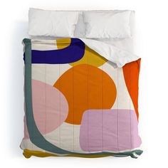 a bed covered in a colorful comforter next to a white pillow and two pillows