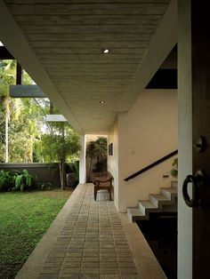 a chair sitting on the side of a brick walkway next to a lush green yard