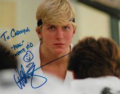 a young man with blonde hair wearing a headset and signed autograph on his shirt