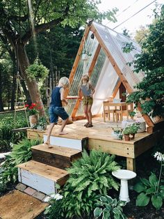 two children are playing on the steps in front of a house that is made out of wood