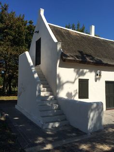 a white house with a thatched roof and stairs