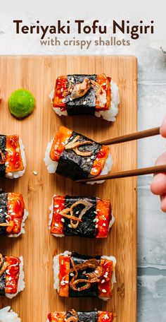 sushi on a wooden board with chopsticks and sauce drizzled over them