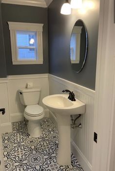 a white toilet sitting next to a sink in a bathroom under a mirror on the wall