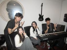 three people sitting in front of an electronic keyboard and giving the peace sign with their fingers