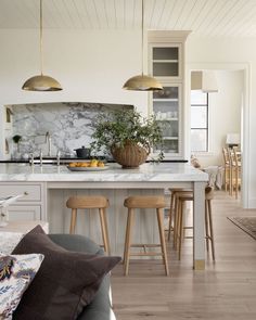 three wooden stools sit in front of an island