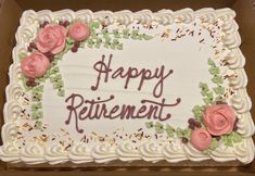 a white cake with pink roses on it in a box that says happy retirement,