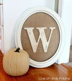 a white frame sitting on top of a wooden floor next to a pumpkin and letter w