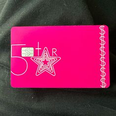 a pink credit card sitting on top of a black cloth covered in writing and stars