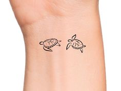 a small tattoo on the wrist of a woman's arm with two turtles in it