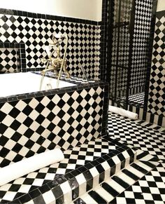 a bathroom with black and white tiles on the walls, floor and bathtub area