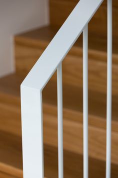 a close up view of a white hand rail on a wooden staircase