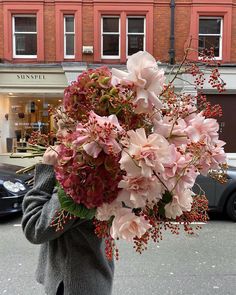 a person holding a bunch of flowers in front of a building