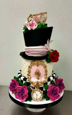 a three tiered cake decorated with roses and an ornate clock on top is sitting on a table