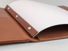 an open leather folder with white paper on the inside and brown trim around the edges