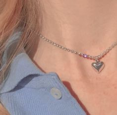 a close up of a person wearing a necklace with a heart charm on it's neck