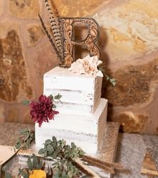 there is a cake that has been decorated with flowers and leaves on the table next to it