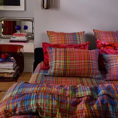 a bed with colorful plaid sheets and pillows