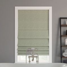 a bath tub sitting next to a window covered in roman shades