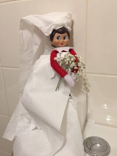 an elf doll is sitting in the bathtub with a bouquet of flowers on it