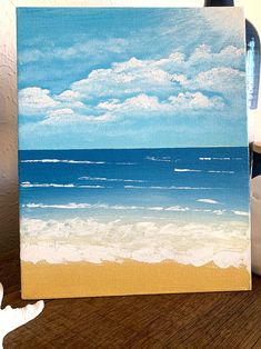 an acrylic painting of the ocean on a wooden table next to a teapot