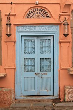 an old blue door is in front of a pink building