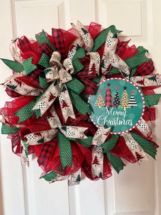 a red and green christmas wreath hanging on a door with the words merry christmas written on it