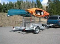 an orange and blue kayak is attached to the back of a trailer in a parking lot