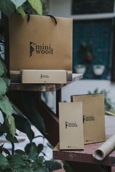 two brown paper bags sitting on top of a wooden table next to a green plant