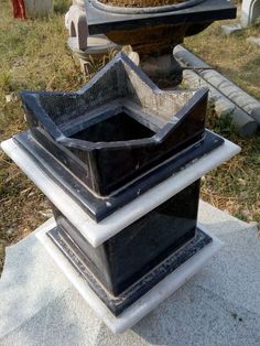 three black boxes stacked on top of each other in front of a grave with grass