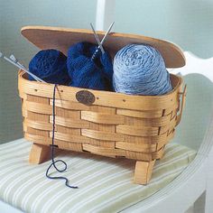 a basket filled with balls of yarn sitting on top of a white chair next to a crochet hook