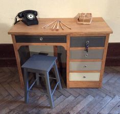 an old fashioned wooden desk with drawers and stools next to a phone on the wall