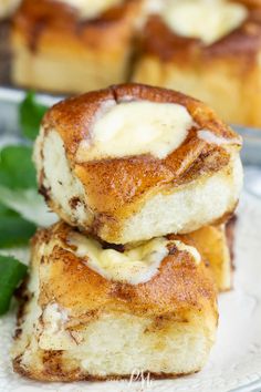 two pieces of cinnamon roll sitting on top of a white plate next to green leaves