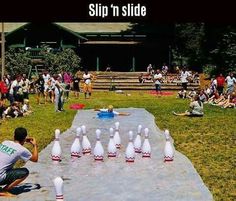 a man squats down to pick up the bowling pins in front of his friends