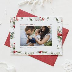 a christmas card with an image of a man and woman holding a baby in their arms