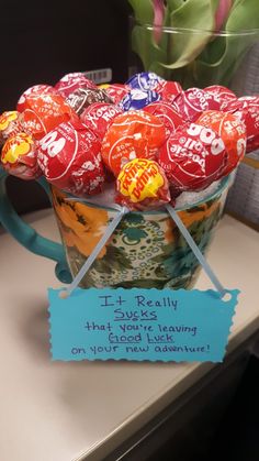 a cup filled with lots of candy sitting on top of a counter next to a sign