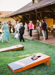 an orange and blue cornhole game sitting on top of green grass next to people