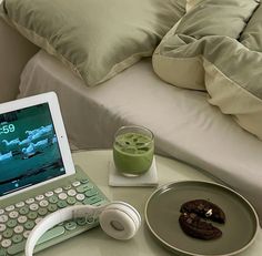 a laptop computer sitting on top of a table next to a cup of green liquid