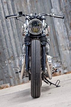 the front end of a motorcycle parked in front of a metal wall with bars on it