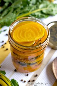 a jar filled with yellow liquid sitting on top of a table next to spoons