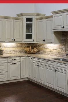 a kitchen with white cabinets and wood floors