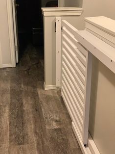 an empty hallway leading to a bathroom with wood flooring and white trim on the walls