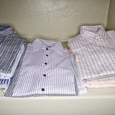 shirts are lined up on a shelf in a closet, with one folded and the other unbuttoned